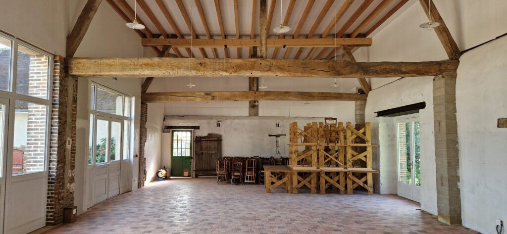 grange pour repas de mariage à la campagne avec tables en bois et chaises anciennes en bois